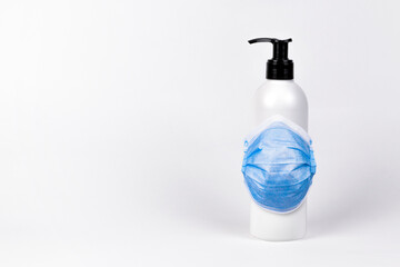 Sanitizer with antibacterial liquid and protective medical face mask. Pump bottle with antimicrobial transparent liquid gel on white background.