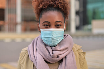 Young attractive black woman in a medical mask smiling - obrazy, fototapety, plakaty