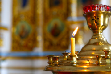 Candles in front of icons in the Orthodox Church. Burning wax candles, cross and icons in the monastery. Christianity. Altar in the church. The concept of the Orthodox faith.