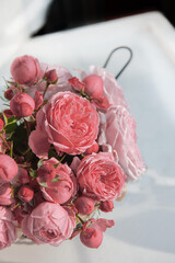 bouquet of pink English roses in a basket on a light table background. Close-up of rose buds, selective focus. Close up