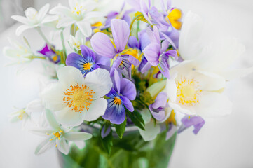 bouquet of small white wild onion flowers and purple pansies in a vase. Close-up, selective focus
