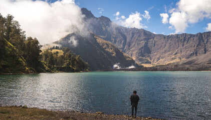 person from the back on the lake, mount Rinjani landscape with lake and mountains, volcano trekking in Indonesia