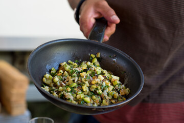 gros plan sur une poêle dans laquelle une personne cuisine des courgettes 
