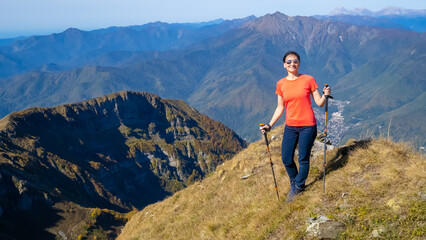 Woman hiker goes hiking, stands on top of mountain and looks at autumn nature mountains landscape in sunny weather. Outdoor activities. Copy space