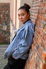 Fototapeta na wymiar Young Mongolian woman wears urban fashion and standing by the brick wall.