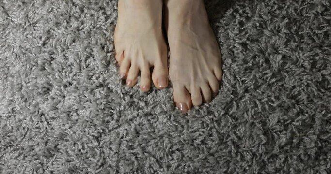 female feet on gray carpet, top view