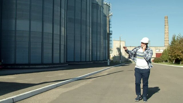 Professional engineer with blueprints inspecting agricultural silos
