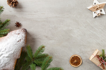 The concept of Christmas card. Homemade pastries, Christmas tree-shaped biscuits, gifts, spruce branches and decorations on a stone table. Top view.