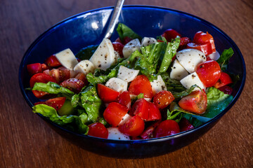 Tomato and cheese salad in a blue bowl