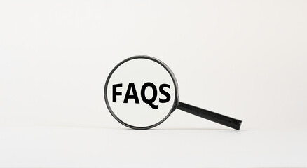 Magnifying glass with text 'FAQS' on beautiful white background. Business concept, copy space.
