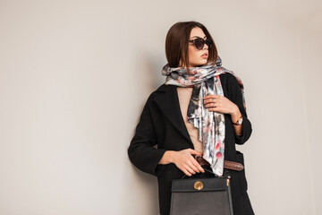 Business young brunette woman in stylish sunglasses in a black coat with a fashionable leather...