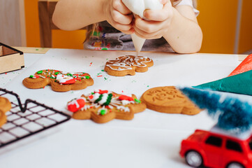 Close up of little girl decorating Christmas gingerbread cookies with icing bag