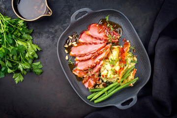 Modern style traditional gourmet duck breast filet with potato salad and beans in orange sauce offered as top view on a modern design plate