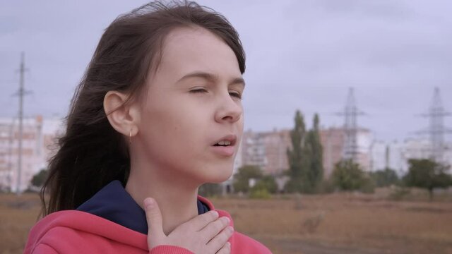 The girl is choking with asthma. Young girl with asthma attack in outdoor.