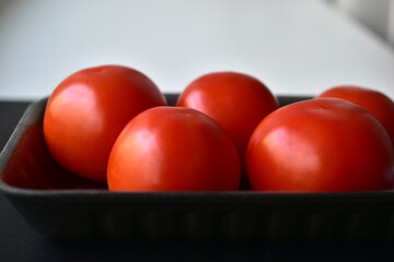 Red ripe tomatoes in a package on a black background