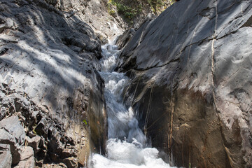 Strong mountain river. Rapid flow of stream among rocks. Blue stream of water seethes in rocks....