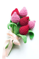 Handmade knitted pink and red tulips on a white background.  Women's hobby. Crocheting and knitting. 
Vertical