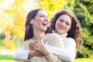 Homosexual couple, two young lesbian women happy laughing, hugging in the park outdoors. Sisters for a walk.