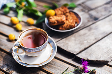 Cup of hot tea and cookies, bowl with yellow plums in   on a wooden table. Coziness and comfort in the house. Thanksgiving day.