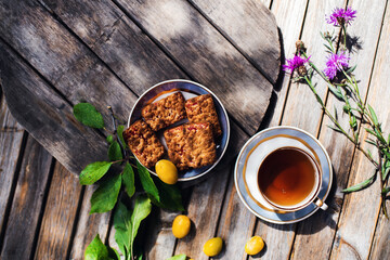 Cup of hot tea and cookies, bowl with yellow plums in   on a wooden table. Coziness and comfort in the house. Thanksgiving day.