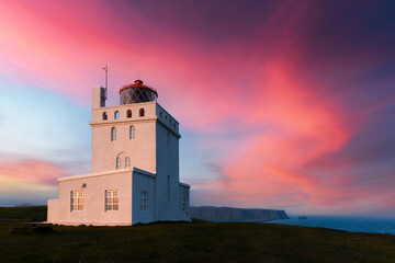 Fototapeta na wymiar Incredible evening view of Dyrholaey Lighthouse at Cape Dyrholaey, south coast of Iceland. Great purple sunset glowing on background. Landscape photography