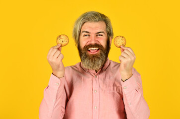 Excited man holding cookies. bearded hipster hold biscuit. full of calorie. concept of harmful food. pastry and dessert. bakery shop advertisement. man on dieting. Man with a biscuit in his hand