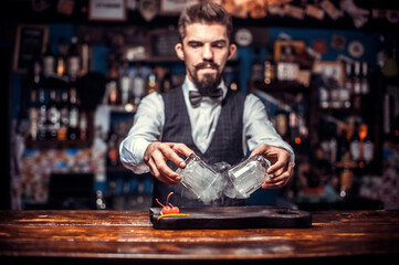 Bearded bartender pouring fresh alcoholic drink into the glasses at bar