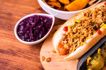 American traditional fast food Hotdog with fresh organic bread bun white wheat and black charcoal sausage ketchup mustard for meal with roasted onion pickle and French fries wedges and coleslaw