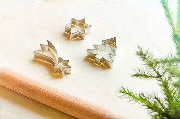 Raw dough for Christmas cookies and cookie cutters. rolling pin, shapes and branches of spruce