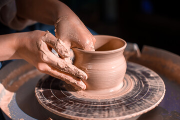 Potter's wheel and the hands of an artisan. Close-up.