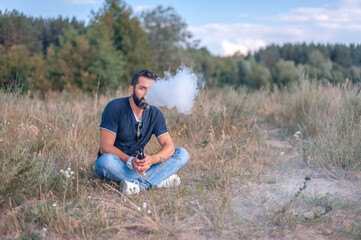 Naklejka na ściany i meble Brutal vape man smoking an electronic cigarette in the outdoors. Getting rid of nicotine addiction.