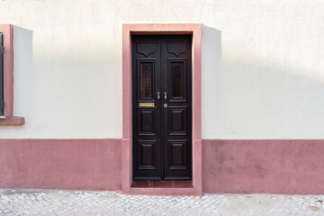 Lisbon, Portugal - 09/27/20: black wooden door with the white and pink wall