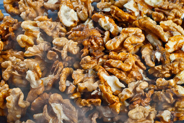 Walnut texture with steam close up. Many halves of peeled nuts. Food in blue smoke. Contrasting dramatic light.