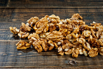 Walnut texture close up. Many halves of peeled nuts on an old wooden board. Food on a background of shabby brown board.