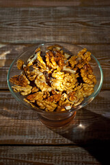 Peeled walnuts in a bowl. Nuts close up on an old wooden board. Food on a shabby table. Contrasting dramatic light as an artistic effect.