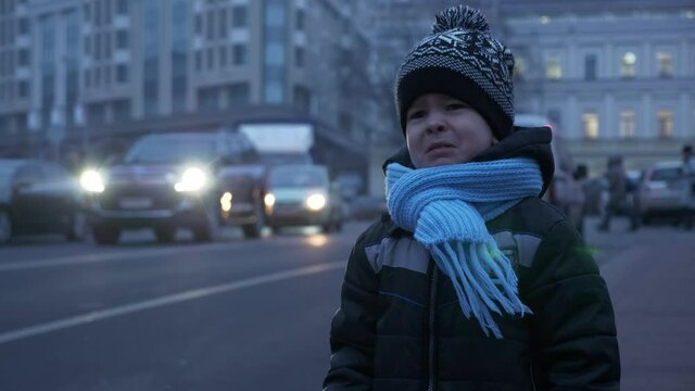 Sad Child Stands Crying Near Busy Road. City Traffic Vehicles Car on Street. Winter Evening Night Traffic Lights. 2x Slow motion 60 fps