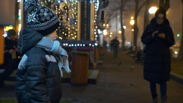 Lost Child Stands Alone. Kind Woman Helping to Find Parents. Evening City Street. Winter Holidays Night. 2x Slow motion 60 fps