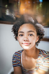 Portrait of pretty teen girl with curly hair in mixed light