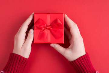 Merry Christmas congratulations concept. Close up top overhead first person view photo of female hands showing small beautiful box with present inside isolated over red background