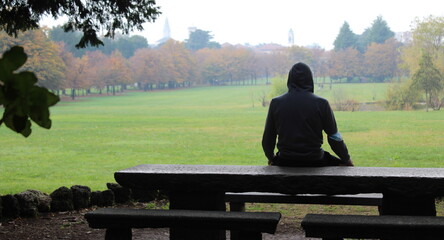 Giovane uomo sulla panchina del parco in autunno - Depressione e solitudine