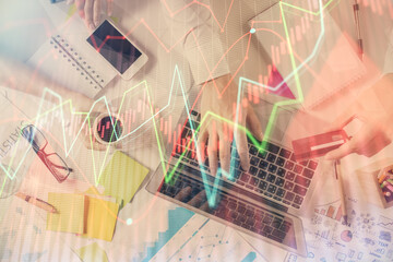 Multi exposure of man's hands typing over computer keyboard and forex graph hologram drawing. Top view. Financial markets concept.