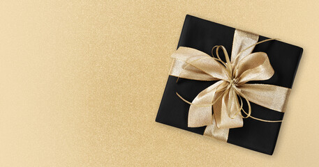 Black Friday gift package wrapped with golden ribbon bow isolated on golden background, template...