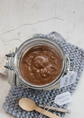 Closeup view of an isolated chocolate mousse jar on a blue knitted napkin next to a couple of spoons.