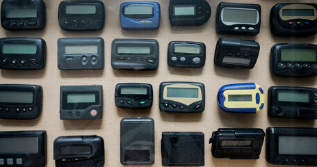  many, a lot old a black pagers or beepers on wooden background. front view.