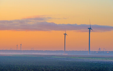 Obraz premium Wind turbine in a yellow sky in bright sunlight at sunrise in an early autumn morning, Almere, Flevoland, The Netherlands, November 5, 2020