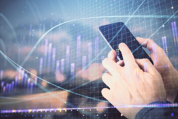 Double exposure of man's hands holding and using a digital device and forex graph drawing. Financial market concept.