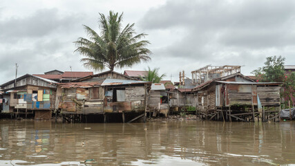 Fototapeta na wymiar Wooden house on Karang Mumus Riverbank. Slum area on Karang Mumus river, Samarinda, Indonesia