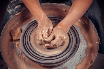 Hands of the master potter and vase of clay on the potter's wheel close-up. Master crock. Twisted potter's wheel.