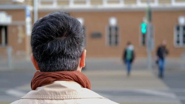 The man and crosses the road when the light turns green. Crossing the road according to the traffic rules. Slow motion