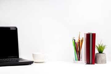 front view for a office or home workplace. white minimal composition with copy space. laptop and stationery on a white desk in front of gray wall background